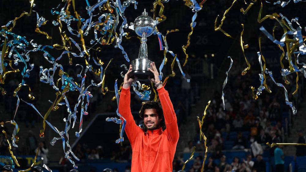 Carlos Alcaraz stemmt eine Trophäe in die Höhe. © APA/afp / RIE KIKUCHI