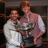 Jannik Sinner und der mittlerweile ehemalige Physiotherapeut Giacomo Naldi posieren mit der Trophäe der Australian Open. © Soziale Medien