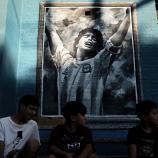 Kinder sitzen vor einem Maradona-Gemälde: Der Argentinier ist auch nach seinem Tod allgegenwärtig. © APA/afp / TOMAS CUESTA