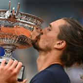Alexander Zverev stemmt erstmals eine Grand-Slam-Trophäe in die Höhe. © APA/afp / JULIEN DE ROSA