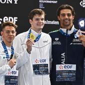 Thomas Ceccon (r.) mit der Bronzemedaille. Daneben: Hubert Kos (Mitte) und Apostolos Siskos. © APA/afp / JULIEN DE ROSA
