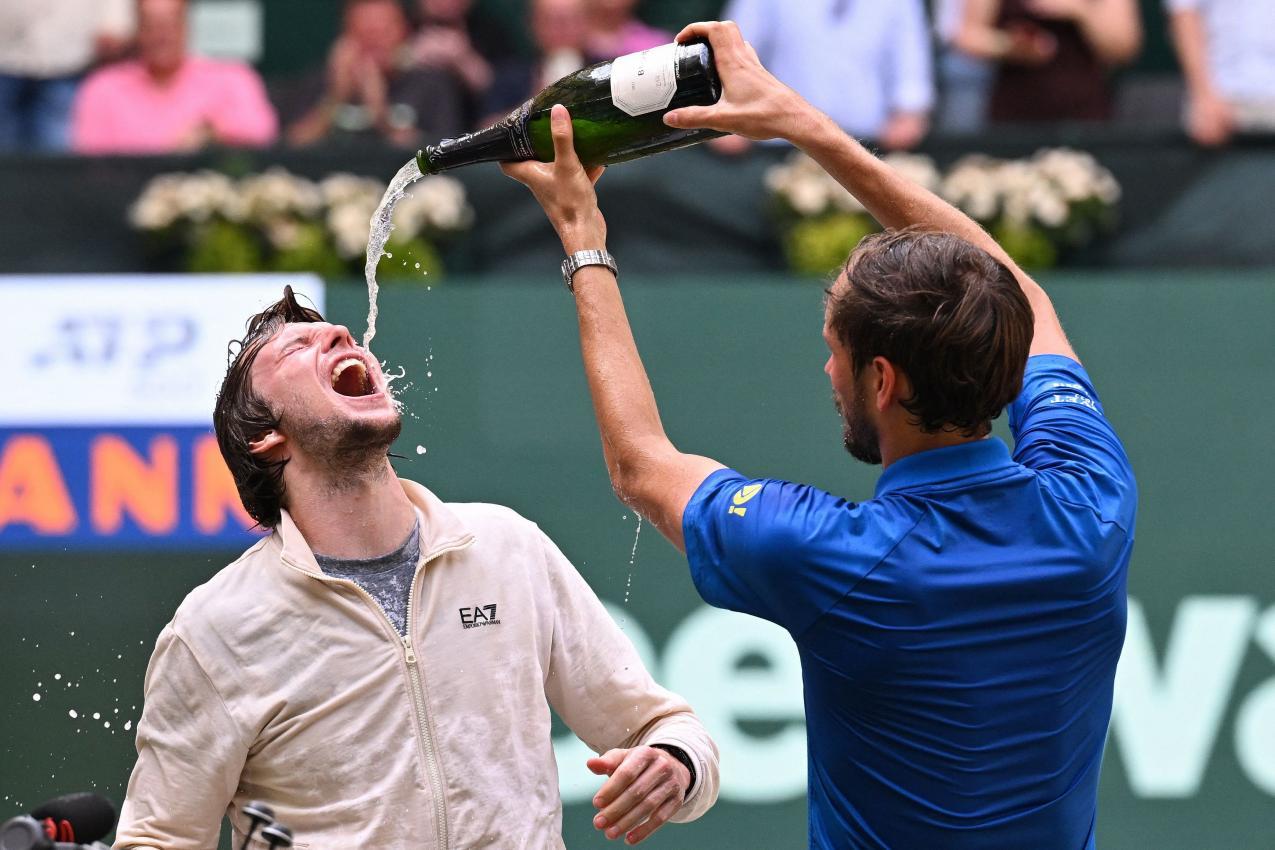 Daniil Medvedev gibt seinem Final-Konkurrenten Alexander Bublik etwas vom Prosecco ab. © APA/afp / CARMEN JASPERSEN