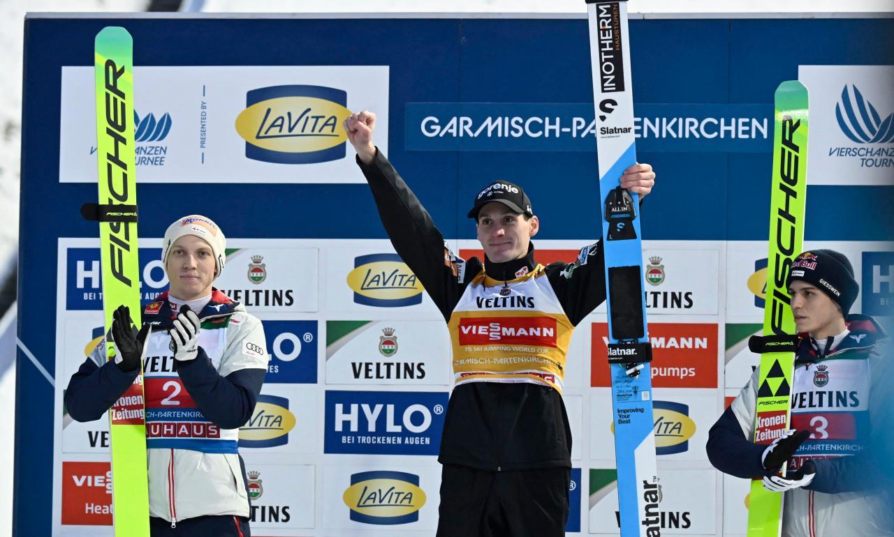 Domen Prevc (center) beams from the winner's podium. © APA/afp / PHILIPP GUELLAND