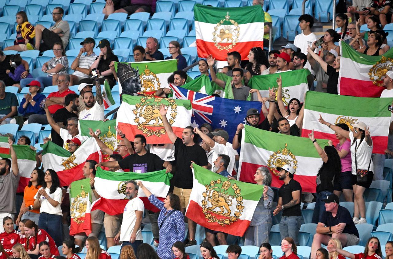 Iranische Fans protestieren mit historischen Flaggen gegen das aktuelle Regime. © ANSA / DAVE HUNT