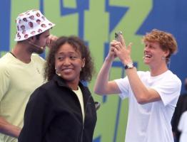 Naomi Osaka ist angesichts des Hütchens sichtlich amüsiert. Im Hintergrund knipst Sinner ein Foto von Khachanov mit seinem Hut.